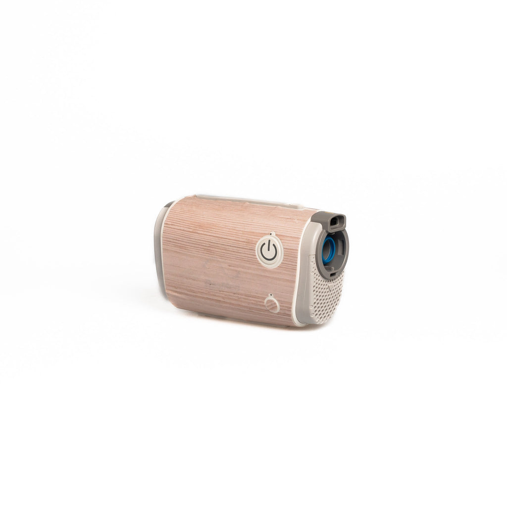 The AirMini Travel CPAP machine dressed in a light wood-patterned skin from Snugell. This subtle design provides a fresh and natural vibe, appealing to users who favor a soft, lightwood aesthetic for their travel essentials.