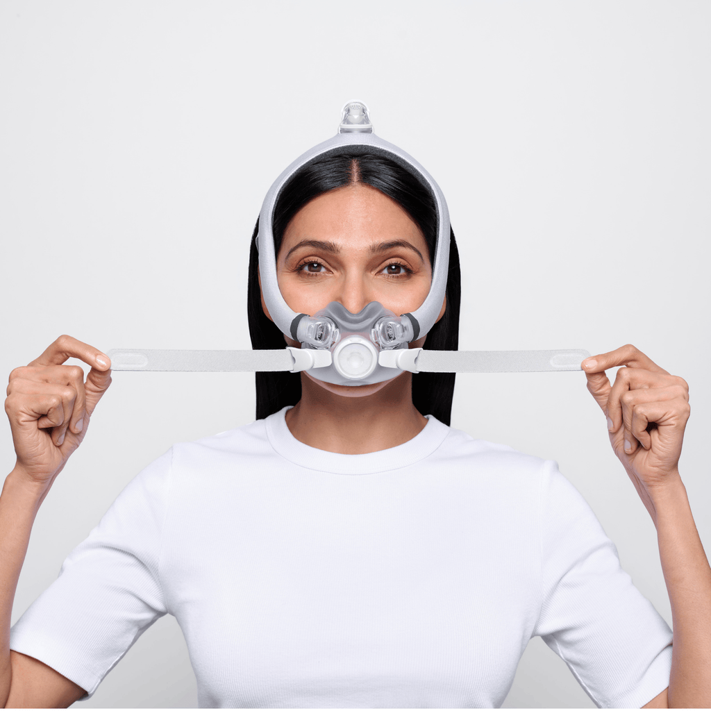 Woman wearing AirTouch F30i Comfort mask adjusts lower headgear straps to dial in her fit.