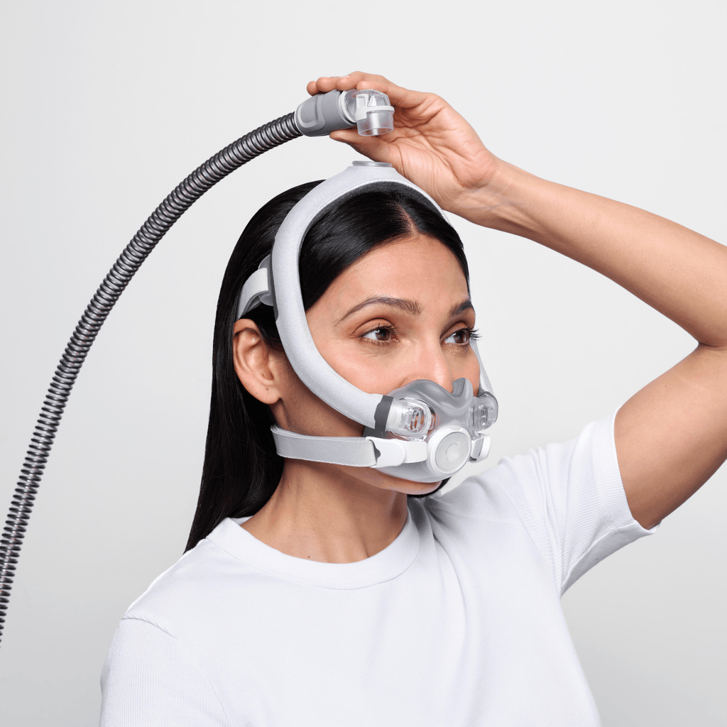 Woman wearing AirTouch F30i Comfort detaches hose from top of head using quick-release elbow.