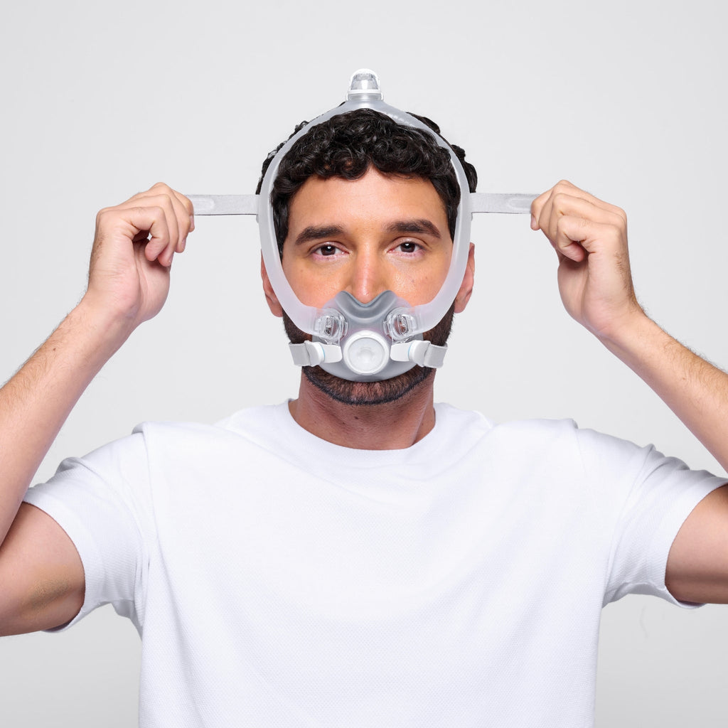 a man wearing the airtouch f30i full face cpap mask adjusts the upper headgear straps